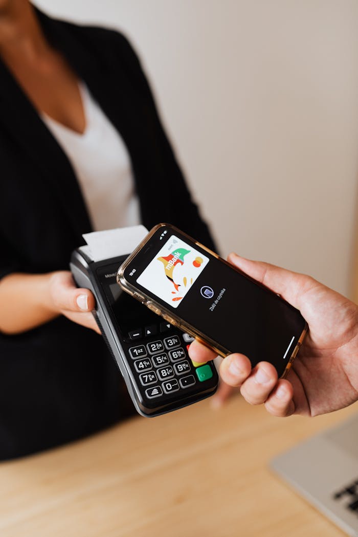 A person pays using a smartphone with contactless technology at a retail payment terminal.